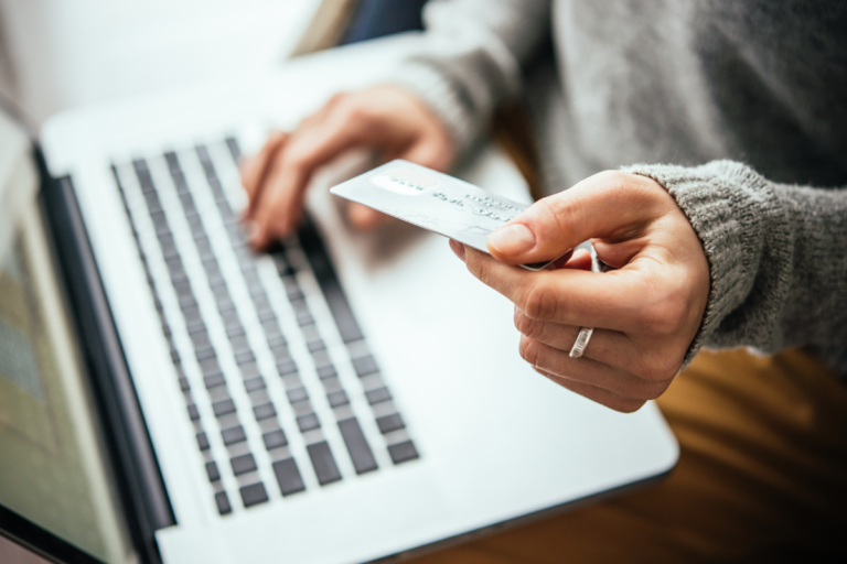 person holding credit card near laptop